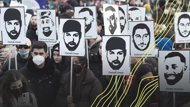 Mit Plakaten und Bildern der Ermordeten erinnern Teilnehmer einer Gedenkveranstaltung auf dem Marktplatz von Hanau an die Opfer der rassistisch motivierten Anschläge von Hanau im Jahr 2020.